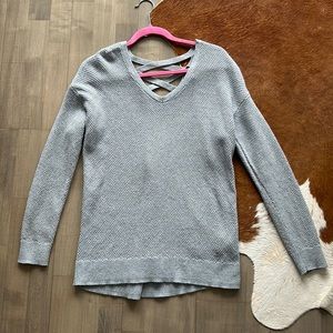 Small “Tribal” brand gray sweater with crisscrossed back pattern.